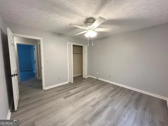an empty room with wooden floor fan and windows
