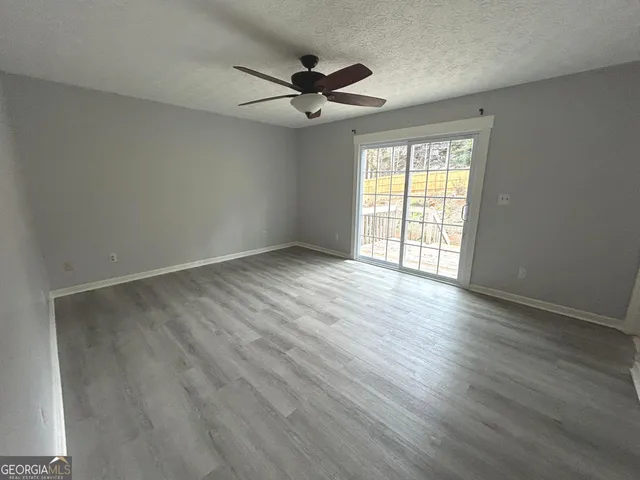 an empty room with wooden floor fan and windows