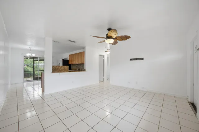 a view of an empty room and a kitchen space with a sink