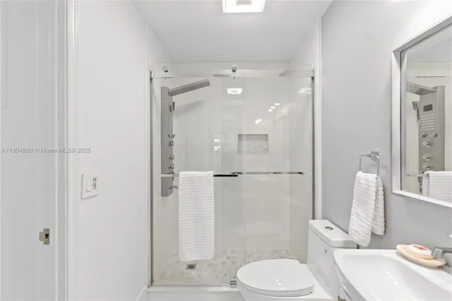 a bathroom with a toilet shower vanity and a sink