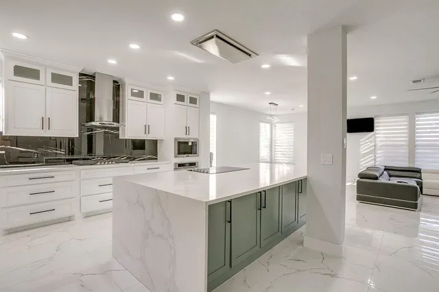 a kitchen with stainless steel appliances kitchen island granite countertop a refrigerator and a stove top oven