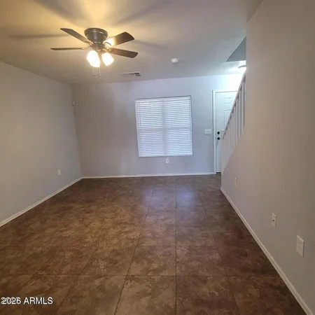 an empty room with a chandelier fan and windows