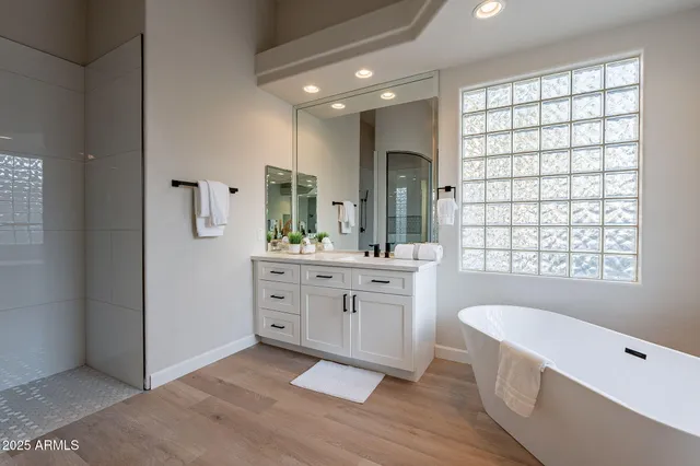 a spacious bathroom with a double vanity sink a large mirror and a bathtub