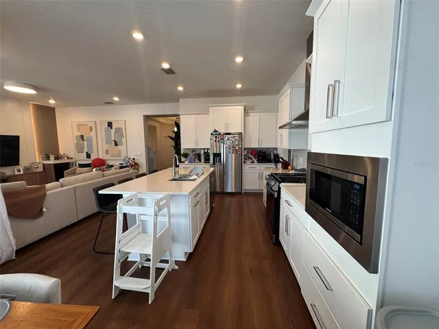 a large white kitchen with stainless steel appliances granite countertop lots of counter top space