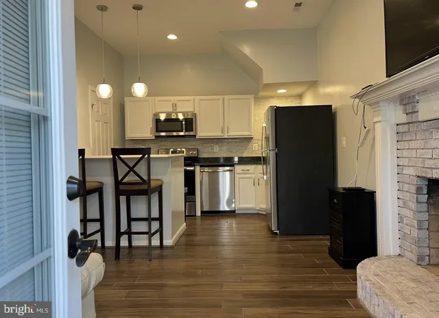 a kitchen with stainless steel appliances granite countertop a refrigerator a stove a sink and a microwave oven with wooden floor