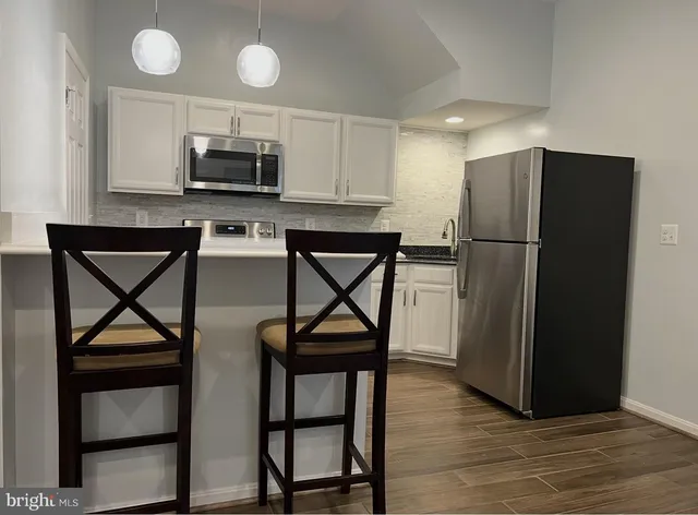 a kitchen with stainless steel appliances granite countertop a refrigerator a microwave a stove and a sink with wooden floor