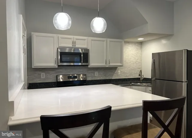 a kitchen with stainless steel appliances a stove a refrigerator a microwave a sink and a stove