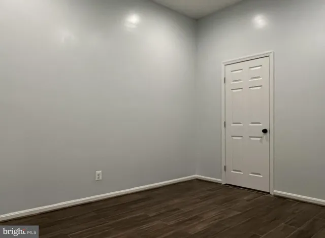 a view of an empty room with wooden floor and closet