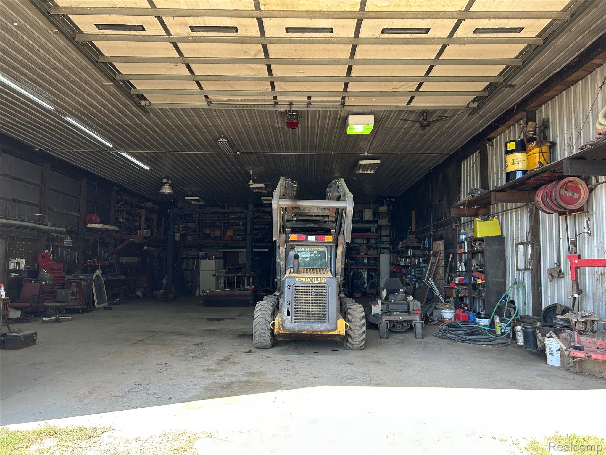 16465 Almont Road Allenton, MI 48002 - Photo 3 of 35 Metal-clad structure featuring a roll-up door, exposed ceiling beams, and concrete flooring