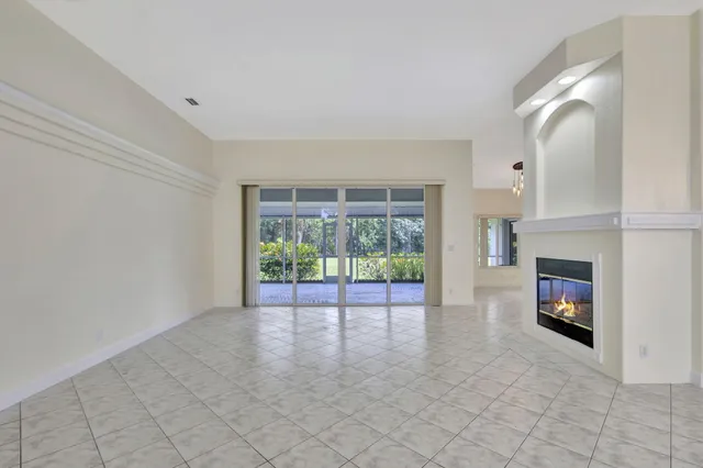an empty room with chandelier fan and windows