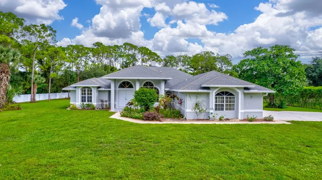 a front view of a house with a garden and trees