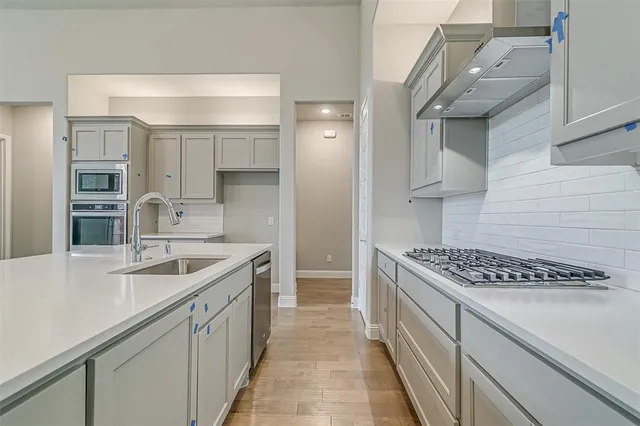 a large kitchen with stainless steel appliances a large counter top a stove a chimney a sink and a window