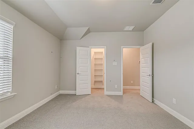 an empty room with chandelier fan and windows