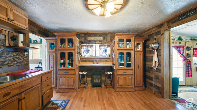 180 North State Street Sigurd, UT 84657 - Photo 20 of 32 Kitchen featuring brown cabinetry, light wood-type flooring, wooden walls, glass insert cabinets, and light countertops