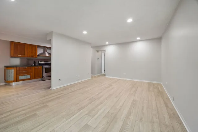 an empty room with wooden floor and stainless steel appliances
