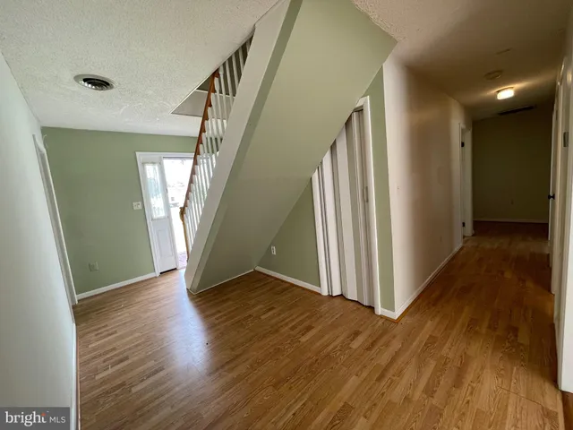 a view of a hallway with wooden floor and stairs