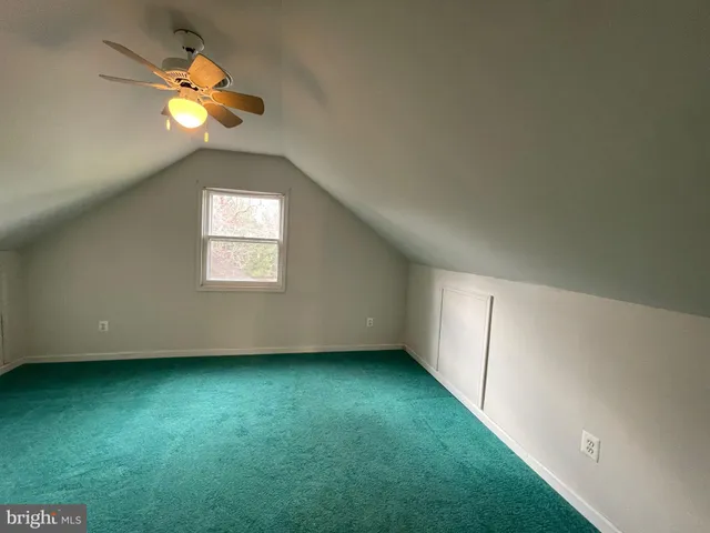 an empty room with a window and chandelier fan