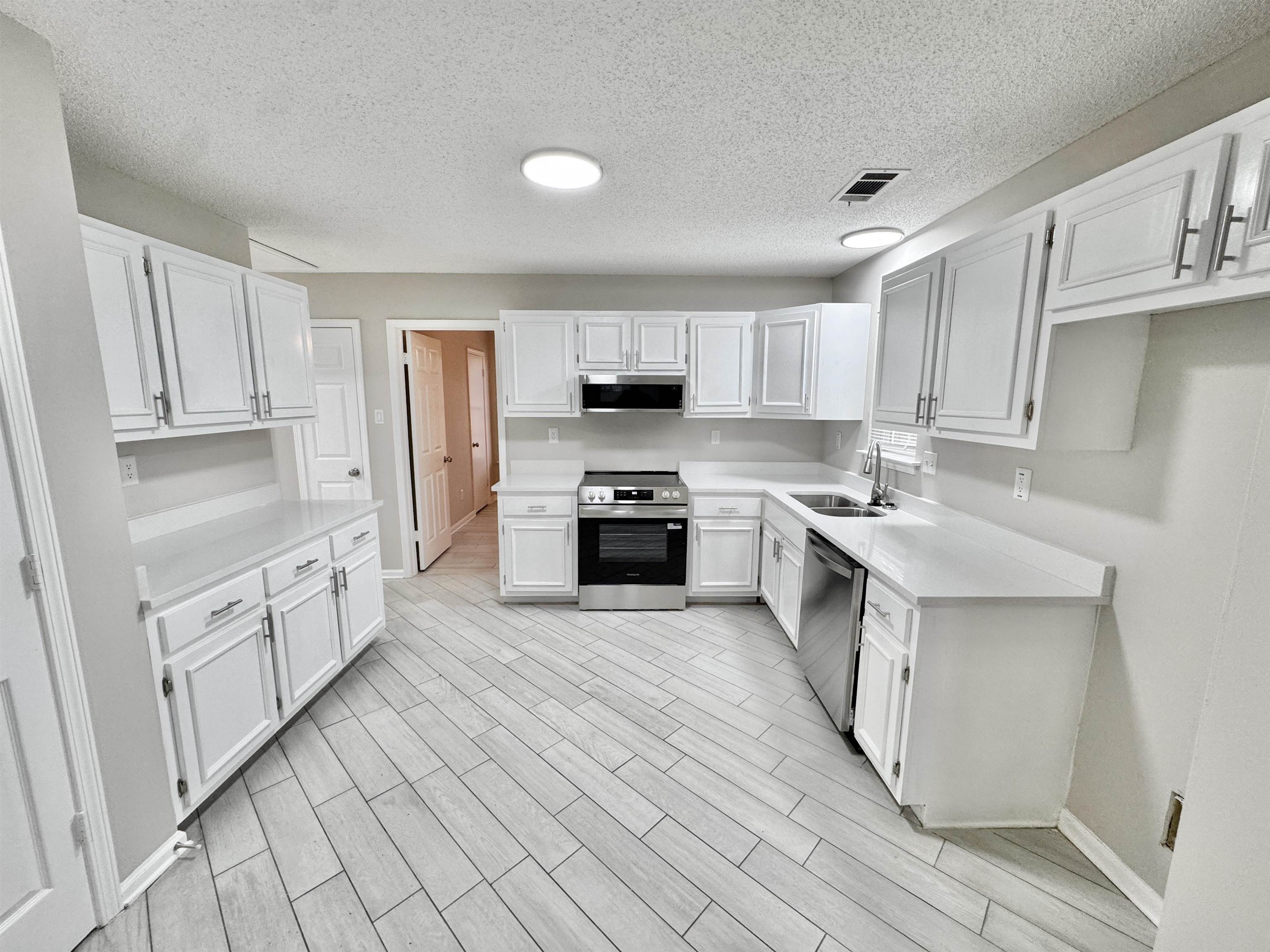6400 Kerrville Rosemark Road Millington, TN 38053 - Photo 8 of 36 Kitchen with stainless steel appliances, white cabinetry, a textured ceiling, and wood finish floors