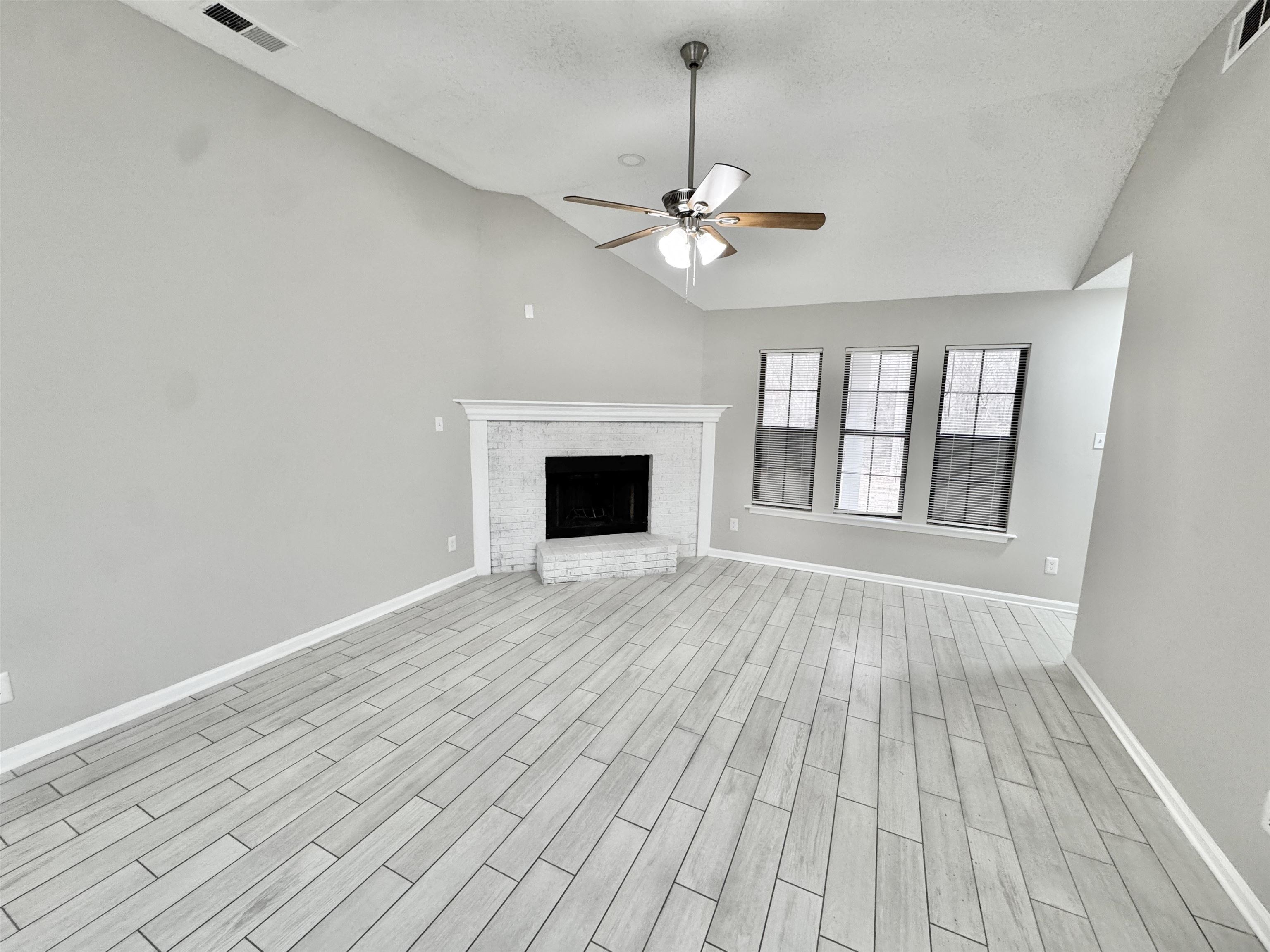 6400 Kerrville Rosemark Road Millington, TN 38053 - Photo 10 of 36 Unfurnished living room with a fireplace, lofted ceiling, wood tiled floors, ceiling fan, and a textured ceiling