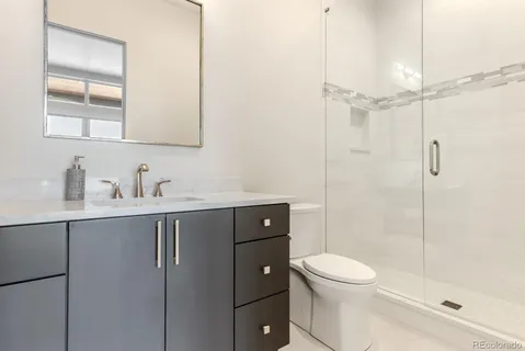 a bathroom with a toilet a sink a mirror a shower and vanity