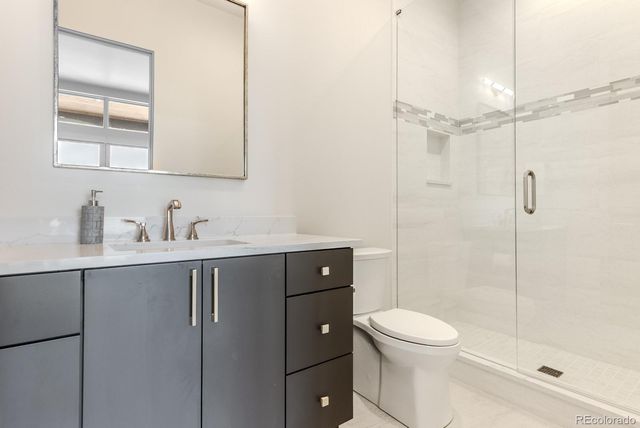 a bathroom with a toilet a sink a mirror a shower and vanity