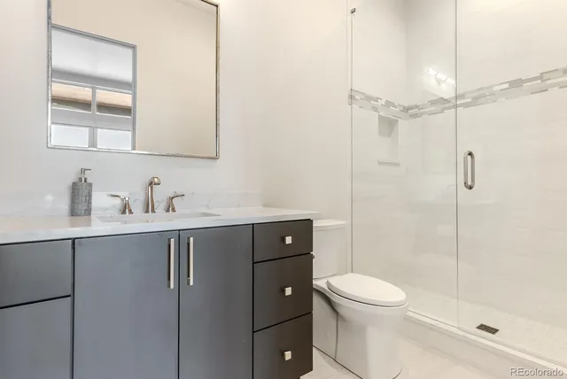 a bathroom with a toilet a sink a mirror a shower and vanity