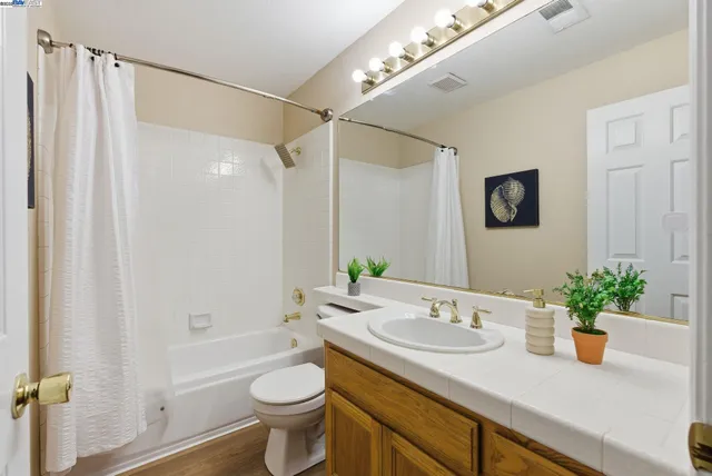 a bathroom with a granite countertop sink a toilet a mirror and shower