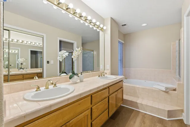 a bathroom with a granite countertop sink a large mirror and a bathtub