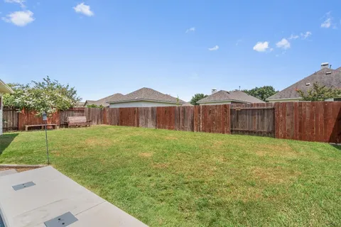 a view of a backyard with table and chairs and wooden fence
