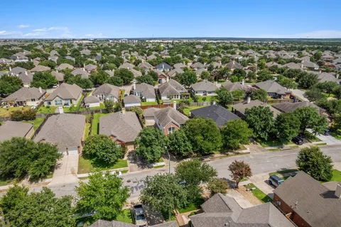 an aerial view of residential houses with outdoor space and trees