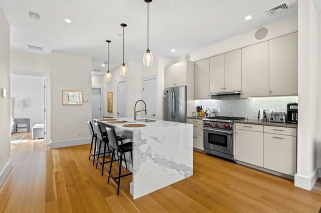 a kitchen with stainless steel appliances granite countertop a stove top oven a refrigerator a sink and a dining table with wooden floor