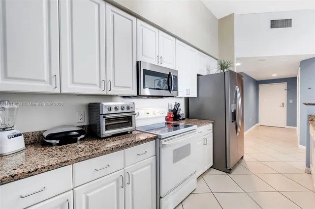 a kitchen with granite countertop white cabinets and stainless steel appliances