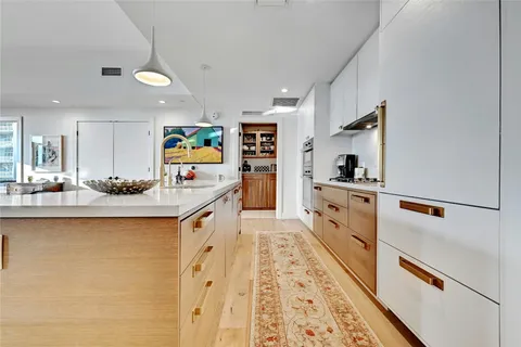 a large white kitchen with stainless steel appliances granite countertop a sink and cabinets