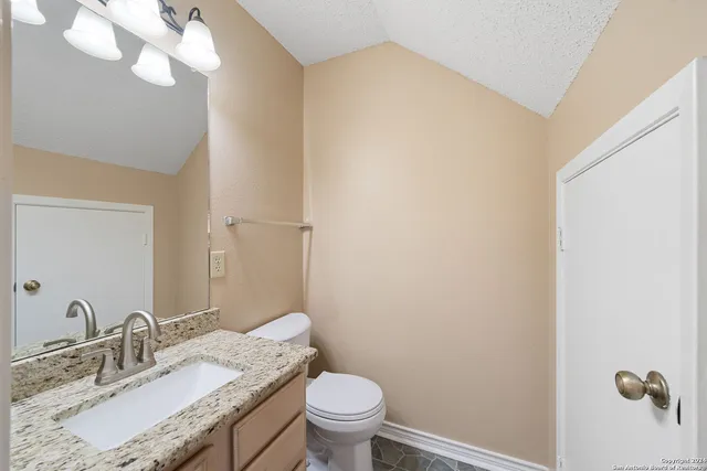 a bathroom with a granite countertop sink a toilet and a mirror