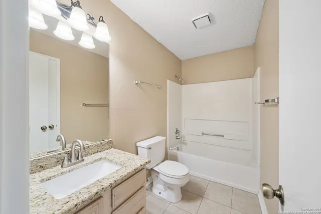 a bathroom with a granite countertop sink mirror vanity and toilet