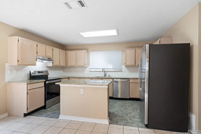 a kitchen with stainless steel appliances granite countertop a refrigerator and a stove top oven