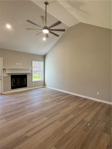 an empty room with wooden floor fireplace and windows