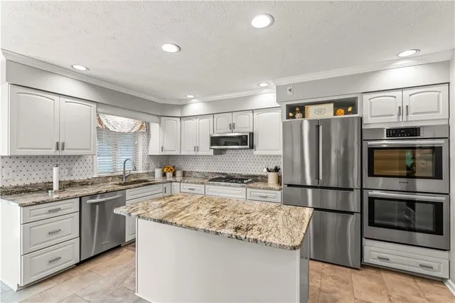 a kitchen with stainless steel appliances granite countertop a sink stove microwave and refrigerator