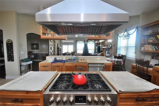 a kitchen with stainless steel appliances granite countertop a stove a sink and a dining table