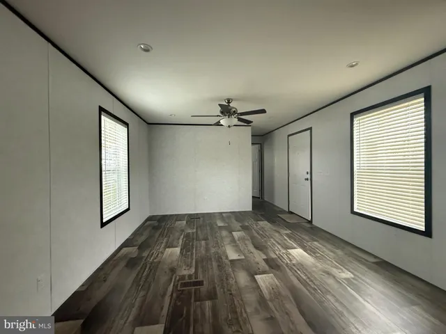 a view of empty room with wooden floor and ceiling fan