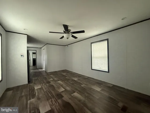a view of empty room with wooden floor and fan