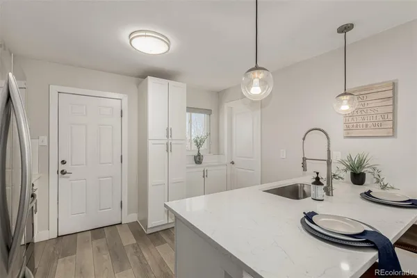 a white kitchen with a sink a stove and white countertops with wooden floor