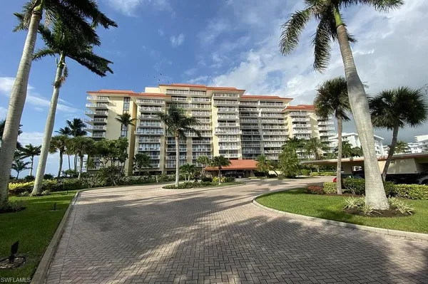 a front view of multi story residential apartment building with yard and green space