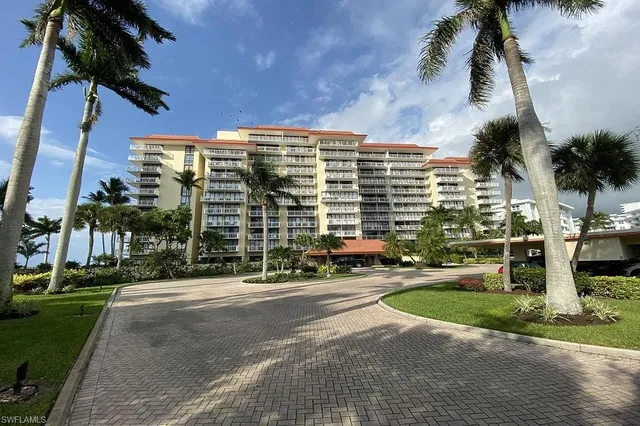 a front view of multi story residential apartment building with yard and green space