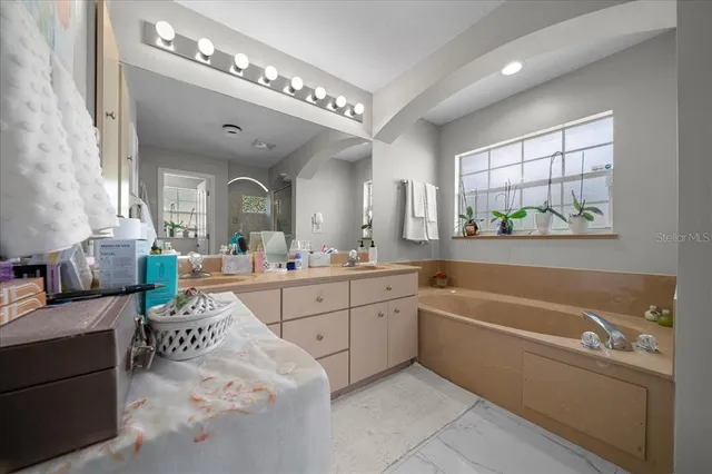 a spacious en suite bathroom with a double vanity sink a mirror a bathtub and next to a window