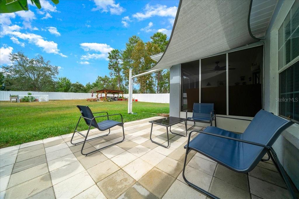4997 Southwest 107th Loop Ocala, FL 34476 - Photo 38 of 48 a view of a patio with a table chairs and a yard