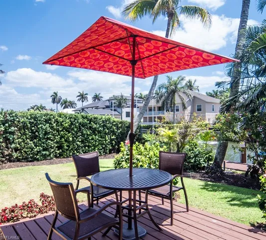 a patio with wooden floor a yard a table and chairs