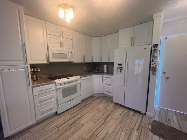 a kitchen with white cabinets and white appliances
