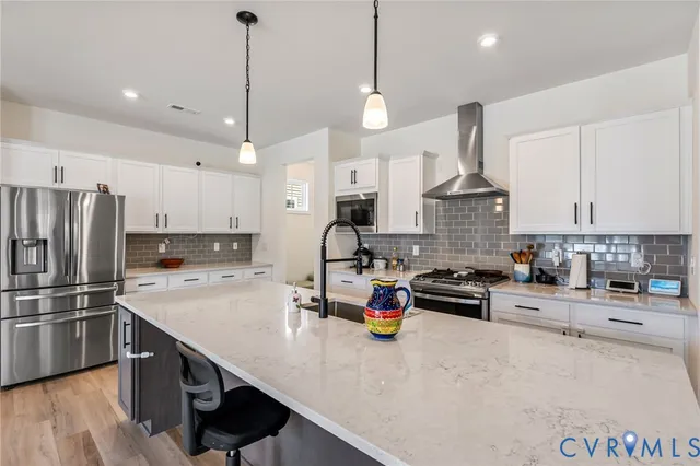 a kitchen with stainless steel appliances a sink a stove a refrigerator and white cabinets