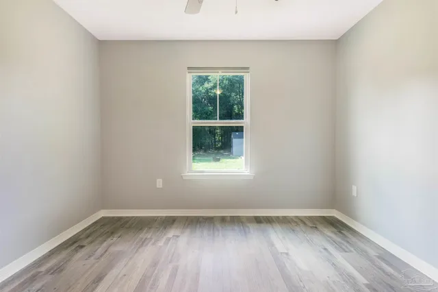 an empty room with wooden floor and a ceiling fan